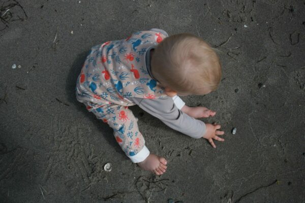 Kind im Strampler am Strand